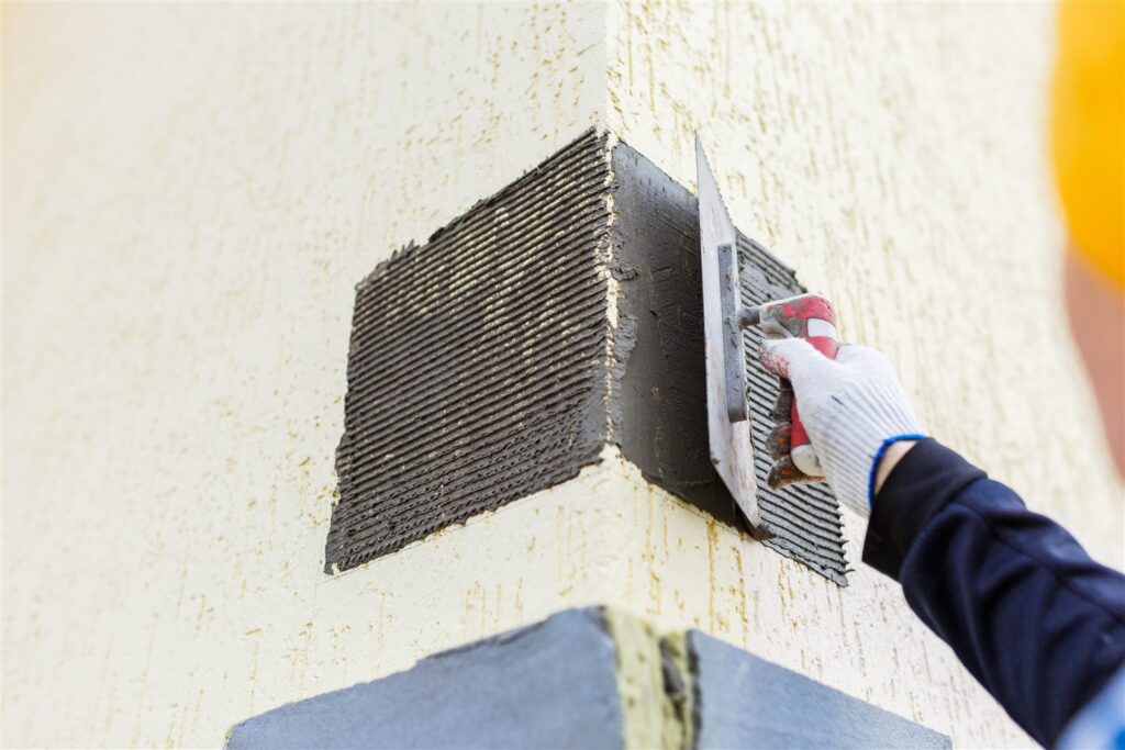 Application d’un enduit de façade à la truelle sur un mur extérieur